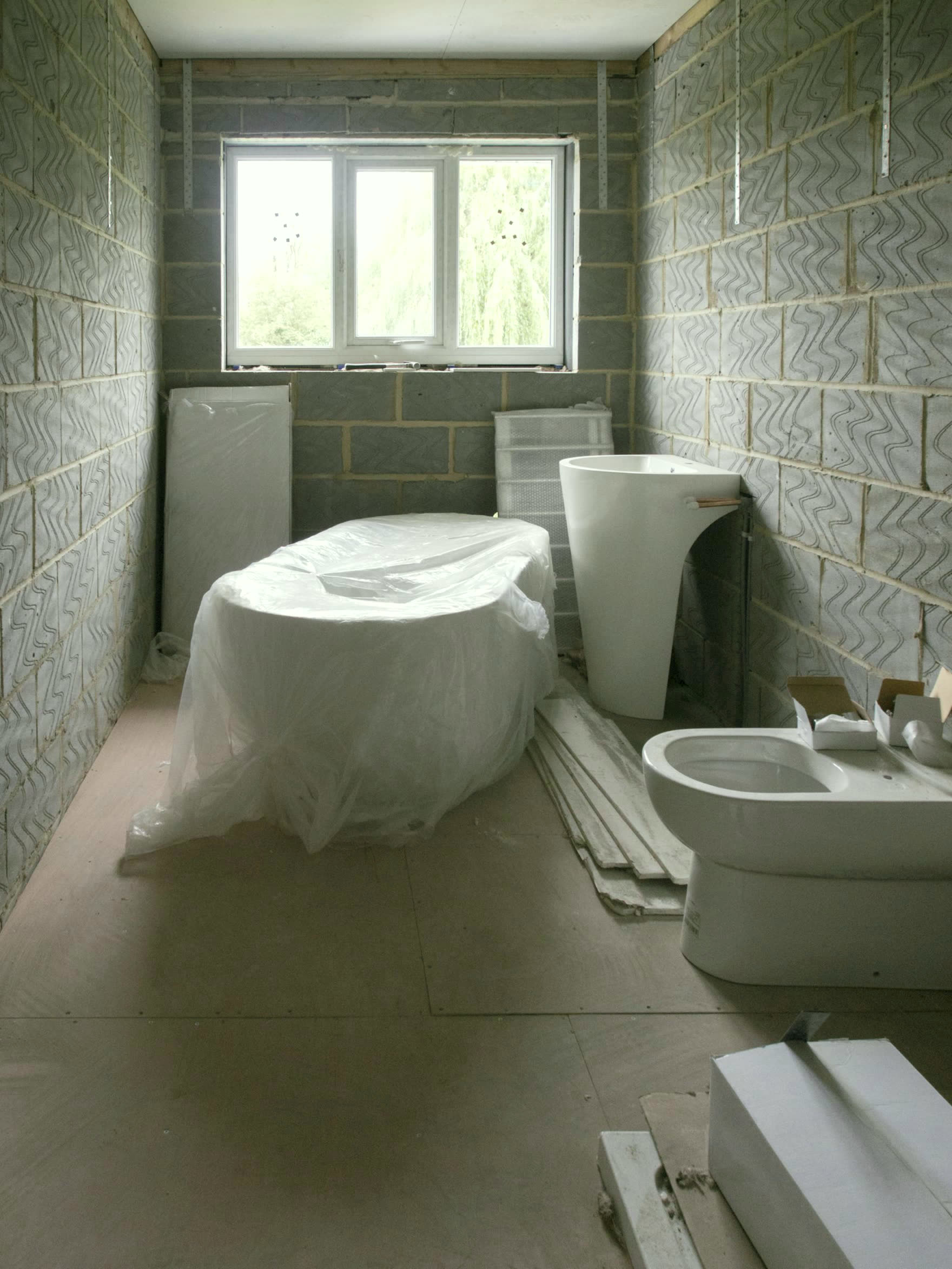 Montaj aşamasındaki banyo; korunaklı vitrifiye ve ham duvarlar
